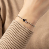Bracelet with a butterfly charm on a wrist against a beige background
