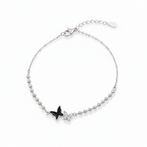 Silver bracelet with a black butterfly charm on a white background