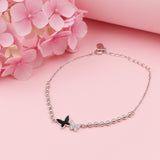 Silver bracelet with butterfly charm on a pink background with pink flowers