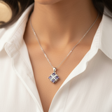 Woman wearing a silver necklace with a pendant against a blurred background