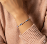 Bracelet with blue evil eye beads on a wrist against a beige sweater background