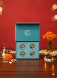 Teal box with coins on a wooden table with decorative elements against a red background