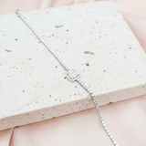 Silver bracelet on a textured white surface with a soft pink background