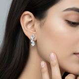Woman wearing a pair of earrings with a neutral background