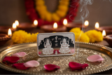 Silver deity bar on a decorative tray with flowers and candles