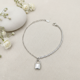 Silver bracelet with a lock charm on a light background with flowers