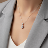 Necklace with a pendant worn by a woman in a gray blazer.