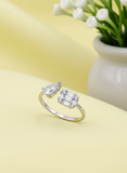 Silver ring with two diamonds on a yellow surface with a plant in the background